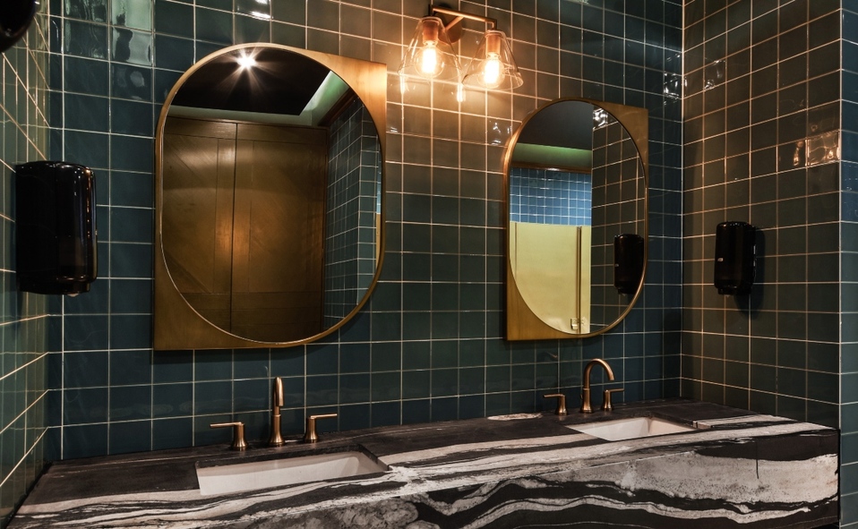 Los baños tienen mayor color con el uso de azulejo verde, espejos con marco de latón y lavabo de mármol negro con blanco.