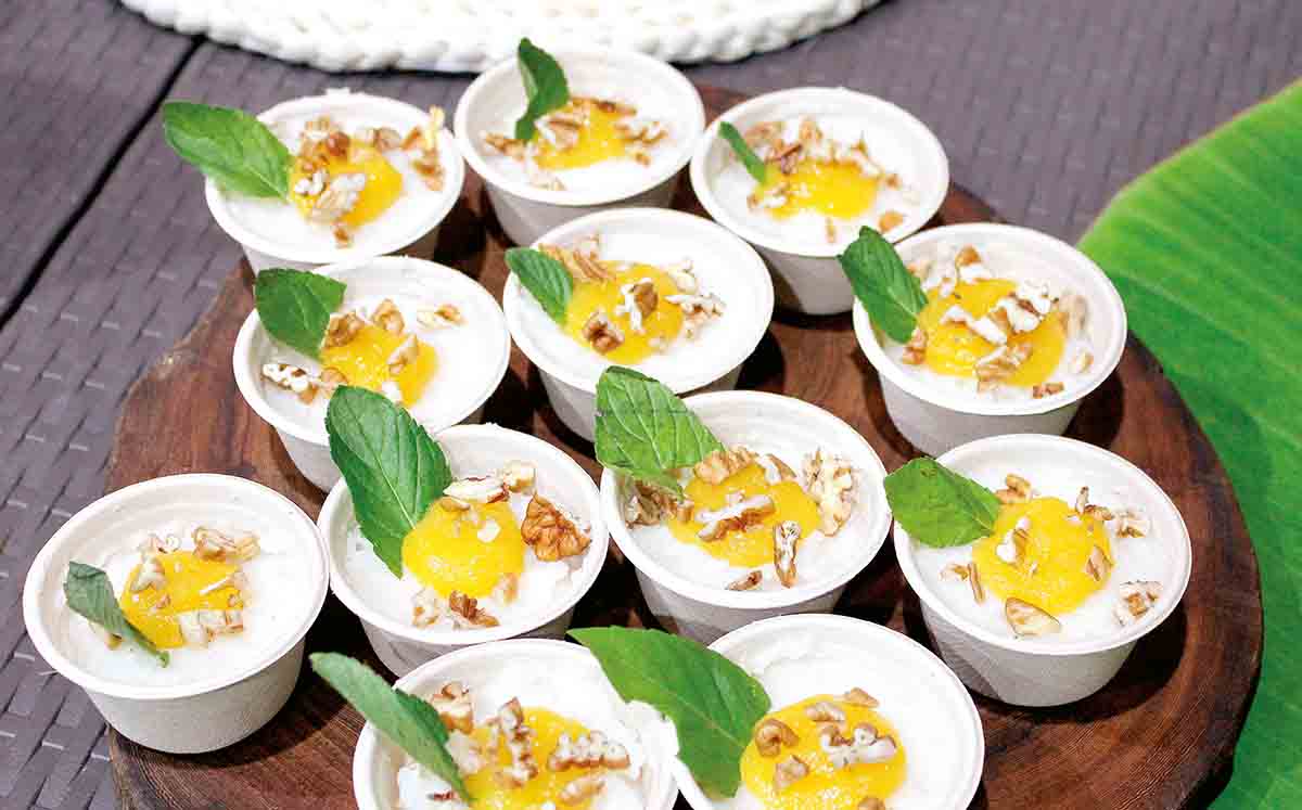 Postre sticky rice con crema de coco y culi de mango con trozos de nuez y menta